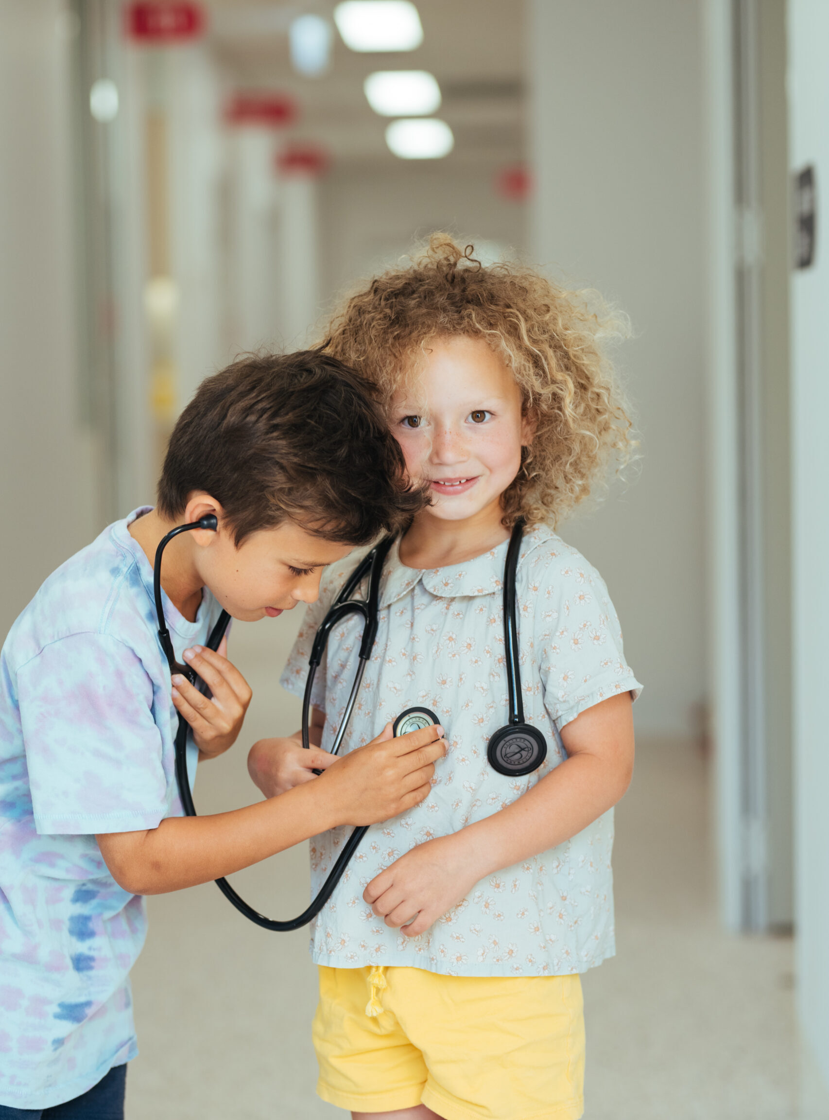 One kid using a stethoscope to listen to another kid's heart
